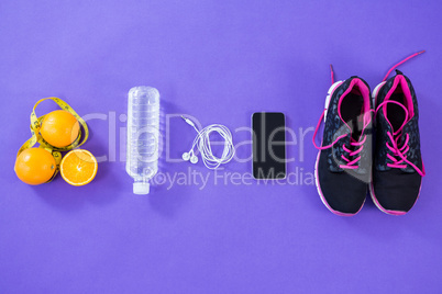Mobile phone with earphones, shoes, water bottle, lemon and measuring tape