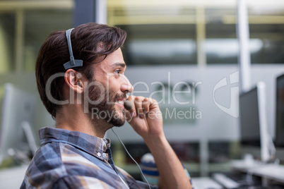 Smiling male customer service executive talking on headset at desk