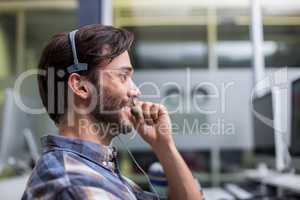Smiling male customer service executive talking on headset at desk