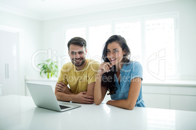 Portrait of couple using laptop in the kitchen