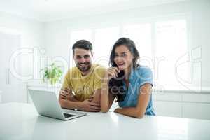 Portrait of couple using laptop in the kitchen