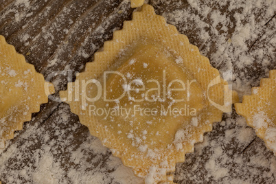 Ravioli pasta dusted with floor on wooden background