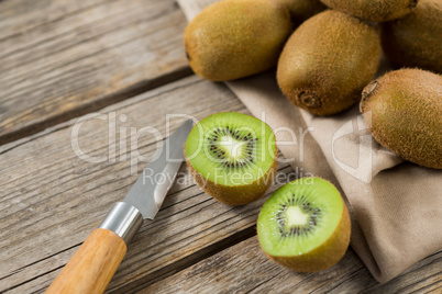 Kiwis with knife on wooden table