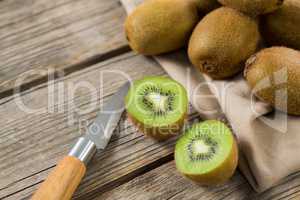 Kiwis with knife on wooden table