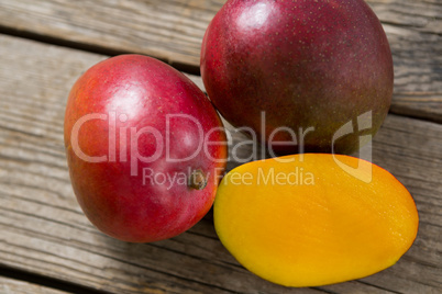 Halved mangoes on wooden table