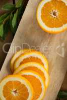 Slices and halved oranges on chopping board