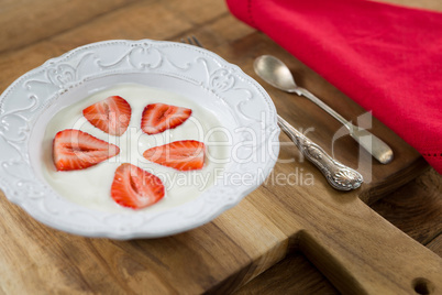 Slices of strawberries in plate with spoon