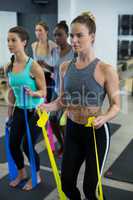 Fit women performing stretching exercise with resistance band