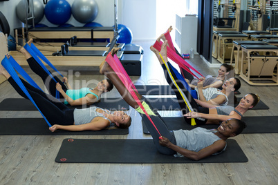 Fit women performing stretching exercise with resistance band in gym