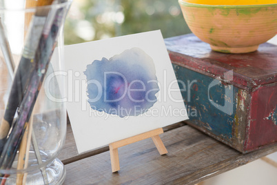 Easel with watercolor paint on wooden surface