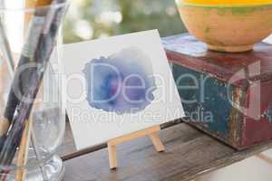 Easel with watercolor paint on wooden surface