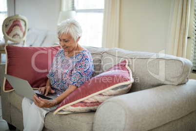 Senior woman using laptop in living room