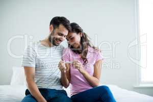 Joyful couple finding out results of a pregnancy test in the bedroom