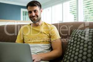 Portrait of man using laptop in living room