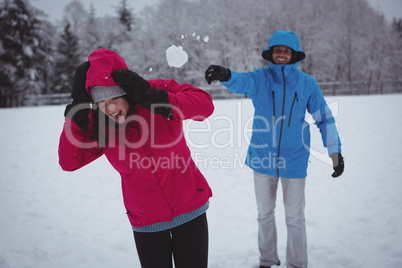 Man throwing snowball at woman