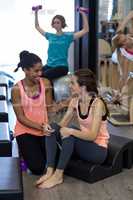 Female trainer assisting woman with stretching exercise on arc barrel