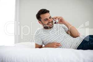 Man talking on mobile phone in bedroom