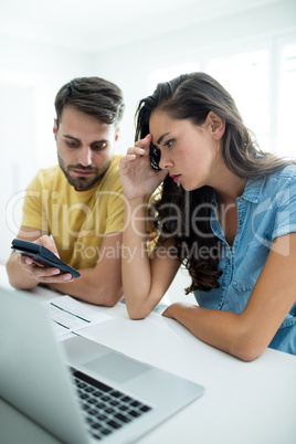 Worried couple calculating their bills with laptop in the kitchen