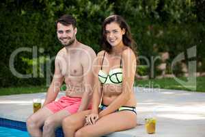 Portrait of young couple sitting at poolside