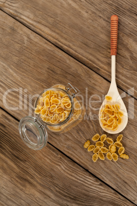 Conchiglie pasta spilling out of jar and spoon