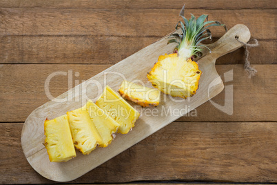 Slices and halved pineapple kept on chopping board
