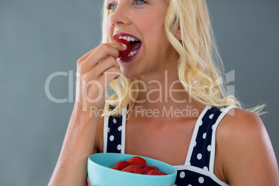 Clos-up of beautiful woman eating strawberries in bowl