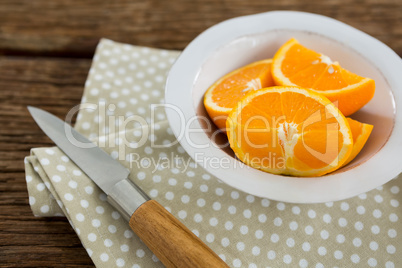 Slices of oranges in bowl on wooden table