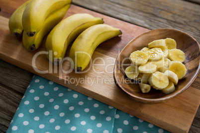 Banana and slices of banana in plate kept on chopping board