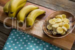 Banana and slices of banana in plate kept on chopping board