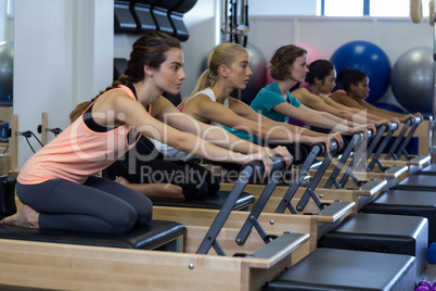 Determined women practicing stretching exercise on reformer