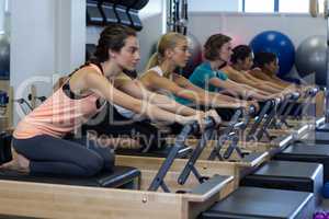 Determined women practicing stretching exercise on reformer