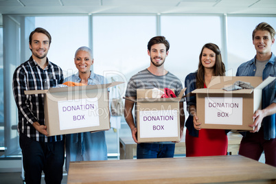 Creative business team holding donation box in office