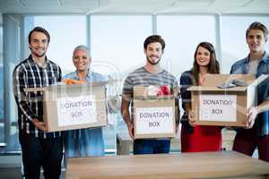 Creative business team holding donation box in office