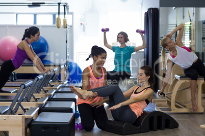 Female trainer assisting woman with stretching exercise on arc barrel