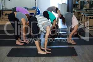 Women performing stretching exercise on exercise mat