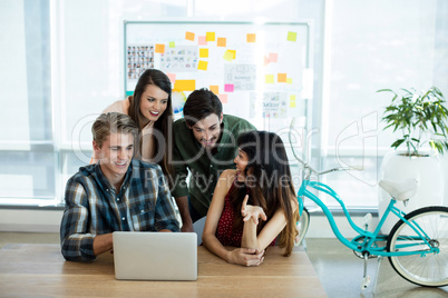 Smiling creative business team discussing over laptop