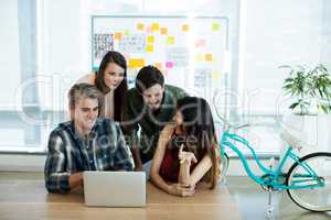 Smiling creative business team discussing over laptop