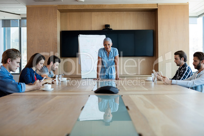 Woman giving presentation to her colleagues in conference room