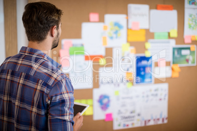 Man with digital tablet looking at sticky notes on the board