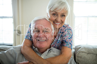 Portrait of happy senior couple embracing each other in living room