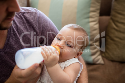 Father feeding milk to baby girl