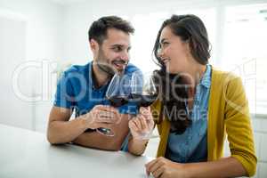 Couple toasting glasses of red wine in the kitchen