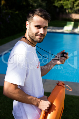 Portrait of lifeguard holding stopwatch at poolside