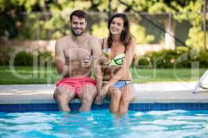Young couple having iced tea at poolside