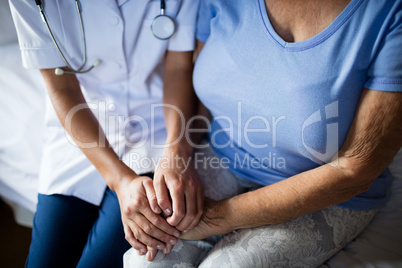 Female doctor consoling senior woman in the bedroom
