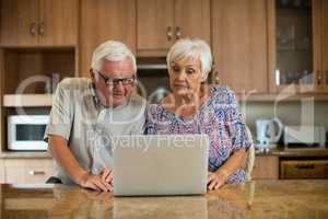 Senior couple using laptop in the kitchen