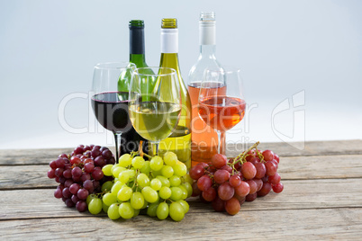 Bunches of various grapes with wine glass and bottles