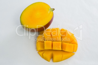 Halved and chopped mango on white background