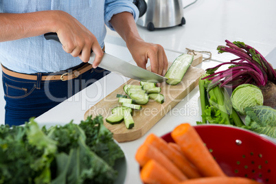 Mid-section of woman cutting vegetables on chopping board