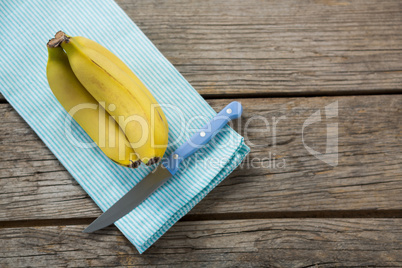 Bananas with knife kept on wooden table